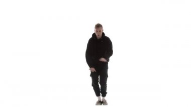 Siyah eşofmanlı genç adam güçlü bir şekilde hip hop, serbest stil, sokak dansı yapıyor. Karmaşık hareketler yapıyor.