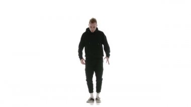 Siyah eşofmanlı genç adam güçlü bir şekilde hip hop, serbest stil, sokak dansı yapıyor. Karmaşık hareketler yapıyor.