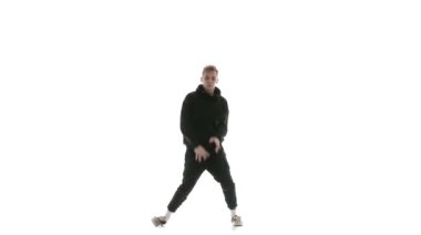 Siyah eşofmanlı genç adam güçlü bir şekilde hip hop, serbest stil, sokak dansı yapıyor. Karmaşık hareketler yapıyor.