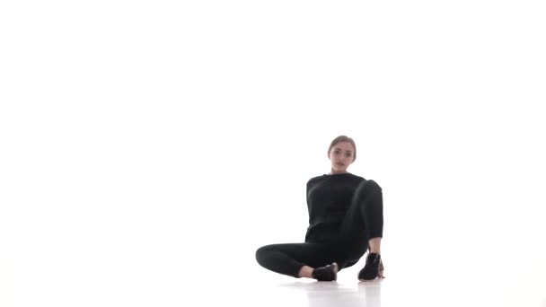 黒のレギンスの若い美しい女性ダンサーと黒のTシャツは 現代的でモダンなストリートダンスを踊り 床の上に美しい動きを実行し 隔離された — ストック動画