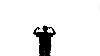 Beyaz arka planda siyah bir siluet, çağdaş sokak dansı yapan genç ve güzel bir kız dansçı, yerde güzel hareketler yapıyor, yavaş çekim.