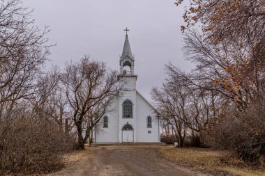 Coderre, Saskatchewan, Kanada 'da ağaçlarla çevrili klasik St. Charles Katolik Kilisesi.