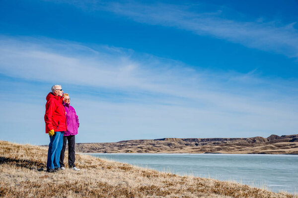 Senior couple standing overlooking an ice-covered Lake Diefenbaker