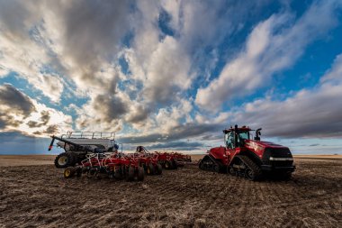 Swift Current, SK / Kanada - 9 Mayıs 2020: Dava traktörü ve Bourgault hava tatbikatı ekipmanları üzerinde gün batımı engin gökyüzü Saskatchewan, Kanada