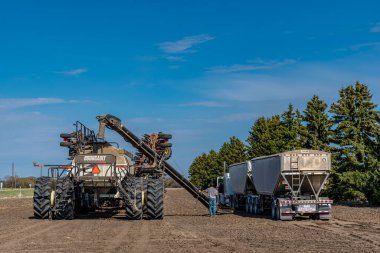 Swift Current, SK / Kanada - 15 Mayıs 2020: Genç çiftçi Saskatchewan, Kanada 'da tohumlamak için Süper B' den Bourgault hava tatbikatına buğday tohumu yüklüyor