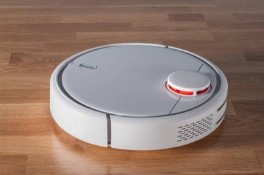 Robot vacuum cleaner runs on wood parquet floor. Modern smart cleaning technology housekeeping