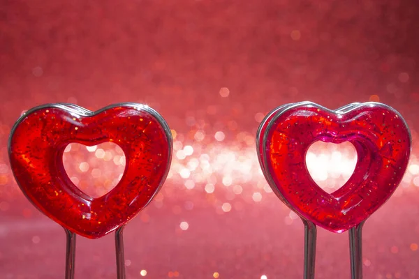 Two red hearts on a stand in the foreground on a red background with bokeh — Stok fotoğraf