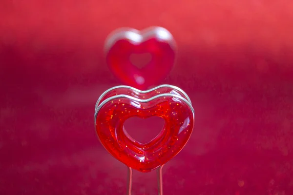 Two red hearts on a stand in the foreground on a red background with bokeh — Stok fotoğraf