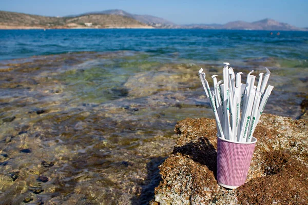 Griekenland. Athene. 13.05.2020. Papier drinkrietjes in papieren bekertje buiten op rotsen naast zee — Stockfoto
