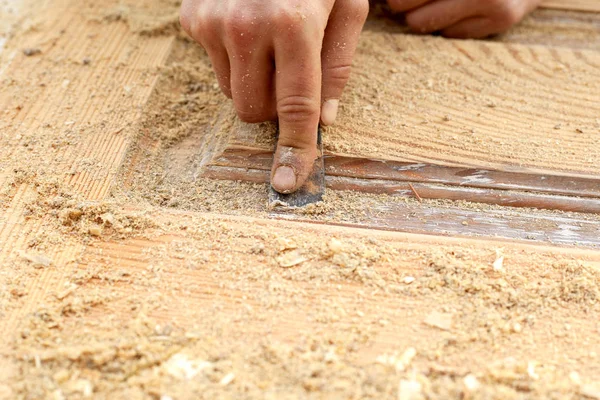 Ahşap kapıların restorasyonu, çalışan bir marangoz spatula.mobilya restorasyon konseptiyle ahşap bir ürünün boyasını soyuyor. — Stok fotoğraf