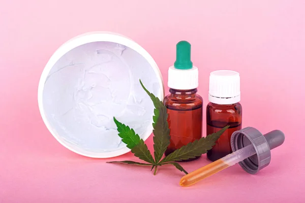 cannabis-based cosmetic oils, bottles with marijuana extract and organic hand and face cream for skin restoration