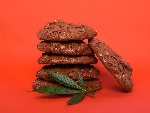 glazed cookies with peanuts and cannabis, recreational drug marijuana cookies on red background