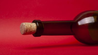 Kırmızı arka planda boş şarap şişesi ve mantar. Alkol romantik içki konsepti