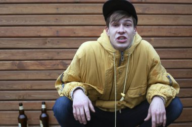 cheeky football fan got drunk beer. stylish young guy in a yellow jacket with an angry face swears