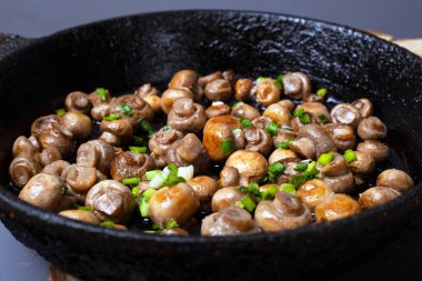 Şampiyon kızararak altın rengine boyanmış ve tavada yeşil soğan var.