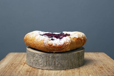 Kirazlı pudra şekeri serpiştirilmiş muhallebi çöreği ve tahta bir orman tezgahının üzerine serpiştirilmiş muhallebi