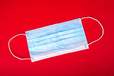 Kırmızı arka planda tek kullanımlık pansuman. Yüz maskesi. Grip virüslerine karşı koruma, Coronavirus covid-2019