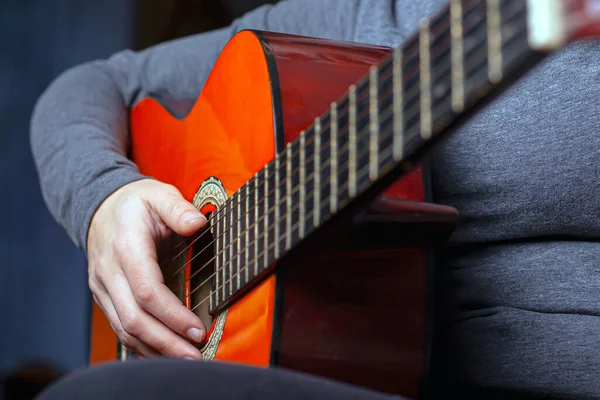 Chica toca una guitarra acústica naranja con cuerdas de nylon —  Fotos de Stock