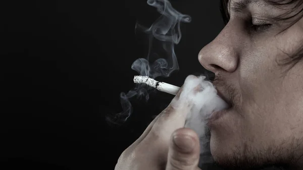 Man smokes a cigarette on dark background. depressed person — Stock Photo, Image
