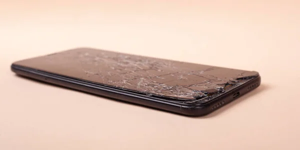 Сломанный телефон на бежевом фоне крупным планом разбитый стеклянный дисплей смартфона — стоковое фото