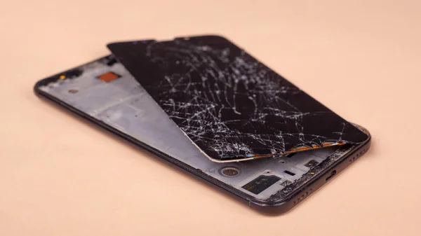 Teléfono roto en un fondo beige pantalla de cristal roto de fondo smartphone pantalla. — Foto de Stock