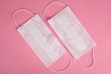 Pembe arka planda beyaz koruyucu tıbbi maskeler. Covid-19 salgını 2020
