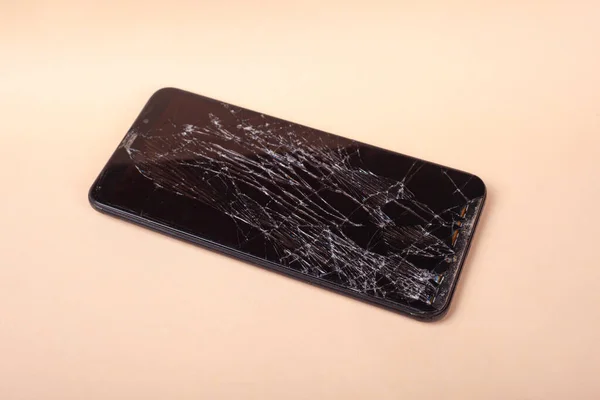 Разбитый сенсорный черный телефон, смартфон, разбитый стеклянный дисплей смартфона на бежевом фоне — стоковое фото