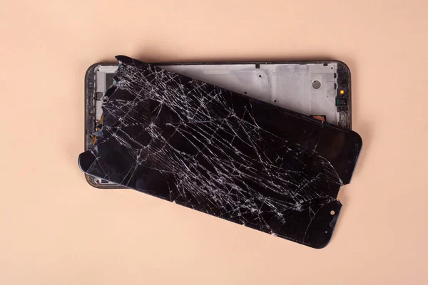 Разбитый сенсорный черный телефон, смартфон, разбитый стеклянный дисплей смартфона на бежевом фоне — стоковое фото