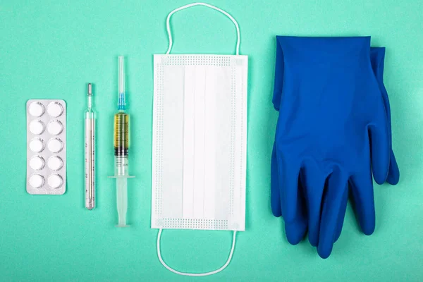 Productos médicos para la protección contra la pandemia de coronavirus covid-19. pastillas jeringa termómetro y máscara médica sobre fondo azul — Foto de Stock