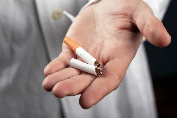 Cigarrillo roto en la mano de un médico de cerca. riesgos para la salud derivados del consumo de tabaco —  Fotos de Stock