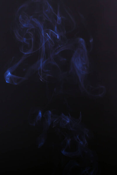White cigarette smoke on a dark black background .