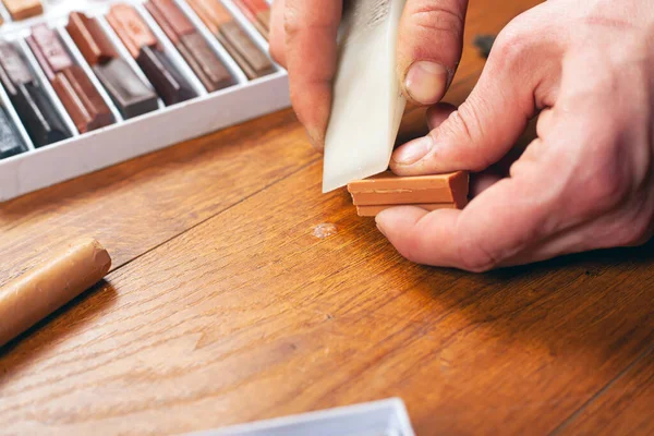 Laminaat en parket restauratie verzegelen krassen en chips. master herstelt een houten oppervlak met waxpotloden close-up — Stockfoto