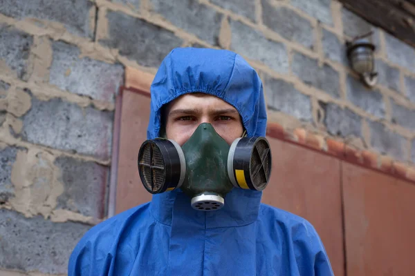 Mann in blauem Schutzanzug und Gesichtsmaske steht in der Nähe eines Backsteingebäudes in Großaufnahme — Stockfoto
