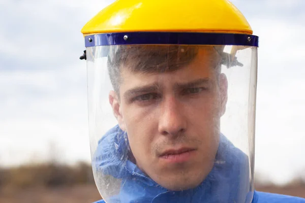 Junger Mann in medizinischer Schutzmaske aus Plastik in Großaufnahme auf der Straße stehend — Stockfoto
