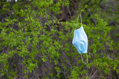 Ağaca asılı tıbbi yüz maskesi. Ekoloji, covid-19 salgınından kaynaklanan çevre kirliliği