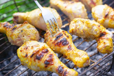 B-B-Q, ızgarada ızgara tavuk budu yakın plan kazıkta kızartılmış. Kabuklu sulu parçalar çatalla ters döner.