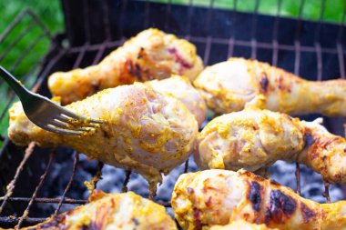 B-B-Q, ızgarada ızgara tavuk budu yakın plan kazıkta kızartılmış. Kabuklu sulu parçalar çatalla ters döner.