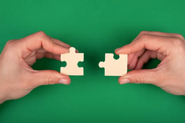Mano di persone che collegano puzzle su uno sfondo verde di soluzioni aziendali e rappresentano il supporto del team — Foto Stock