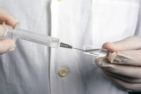 Arts haalt het geneesmiddel uit de ampul door middel van een spuit. behandeling vaccinatie injectiegeneesmiddel virale ziekten covid-19 — Stockfoto