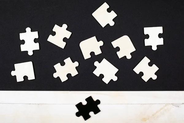 Puzzle in legno bianco su sfondo nero e un puzzle nero su sfondo bianco vista dall'alto . — Foto Stock