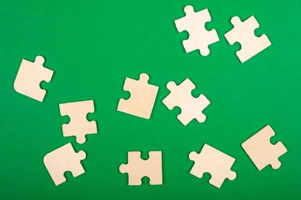 Raccogliere puzzle. pezzi di puzzle sparsi su uno sfondo verde — Foto Stock