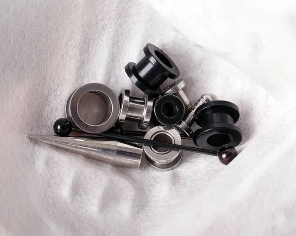 Διάτρηση σήραγγες μαύρο και ασημί χρώμα τεντώσει αυτί κοσμήματα κοντά σε λευκό φόντο — Φωτογραφία Αρχείου