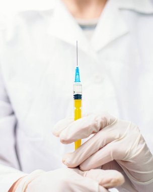 Virüs salgını covid-19. Beyazlı doktor elinde şırınga tutuyor. Koronavirüs salgını aşısı 