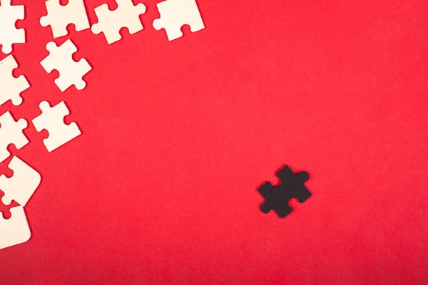 Puzzles en bois blanc et noir sur un fond rouge leader antisocial paria diffèrent des autres jouets éducatifs pour enfants — Photo