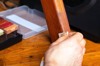 Usta, ahşap mobilya restorasyonundan bir bacağındaki çiziği siliyor. Yakın plan onarım.