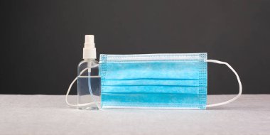 El dezenfektanı şişesi ve tıbbi maske covid-19 enfeksiyon koruması, karanlık arka planda karantina salgını
