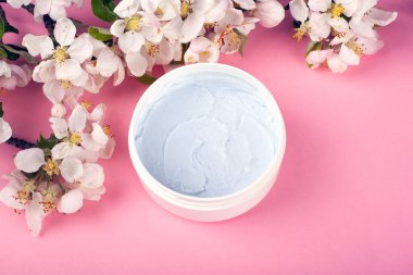 Pembe arka planda beyaz elma çiçekleriyle ovalanan vücut bakımı, kaplıca, güzellik.