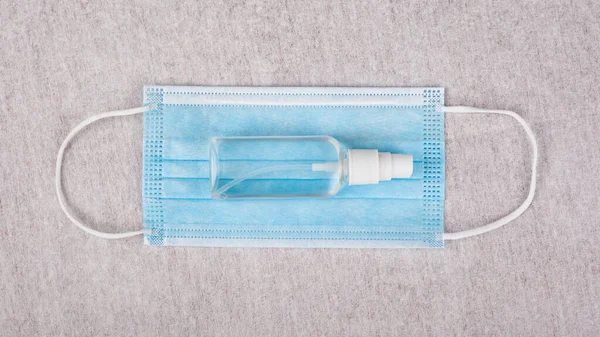 Orvosi kék maszk és palack fertőtlenítőszerrel, kezek fehér háttér felülnézetből közelkép. fertőzés elleni védelem covid-19 — Stock Fotó