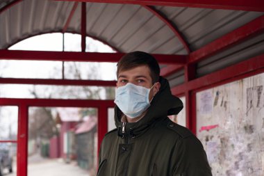 Kamu otobüs durağında beyaz adam ve tıbbi yüz maskesi, covid-19 virüsü, karantina, salgın, salgın, koronavirüs