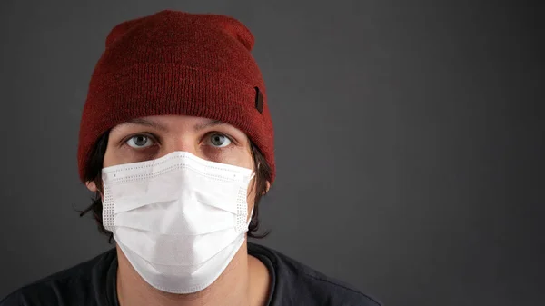 Mann mit medizinischer weißer Maske auf dunklem Hintergrund. Covid-19-Quarantäne-Pandemie der Atemwege — Stockfoto
